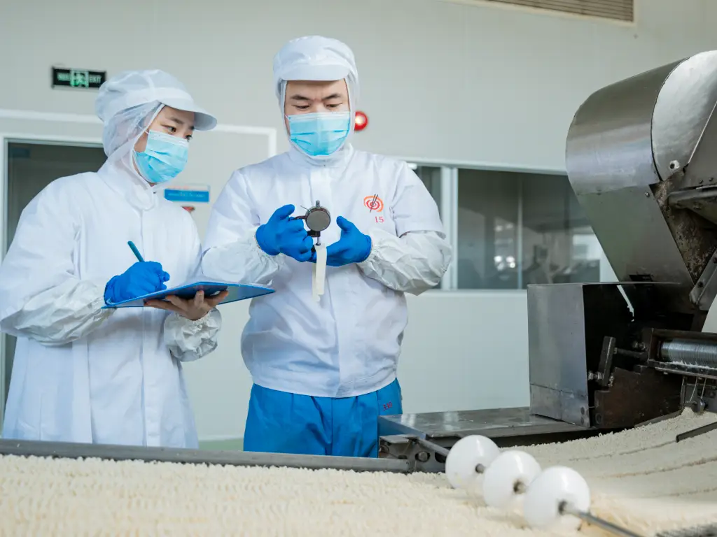 After the noodles are rolled, they are cut and workers are checking whether they meet the standards