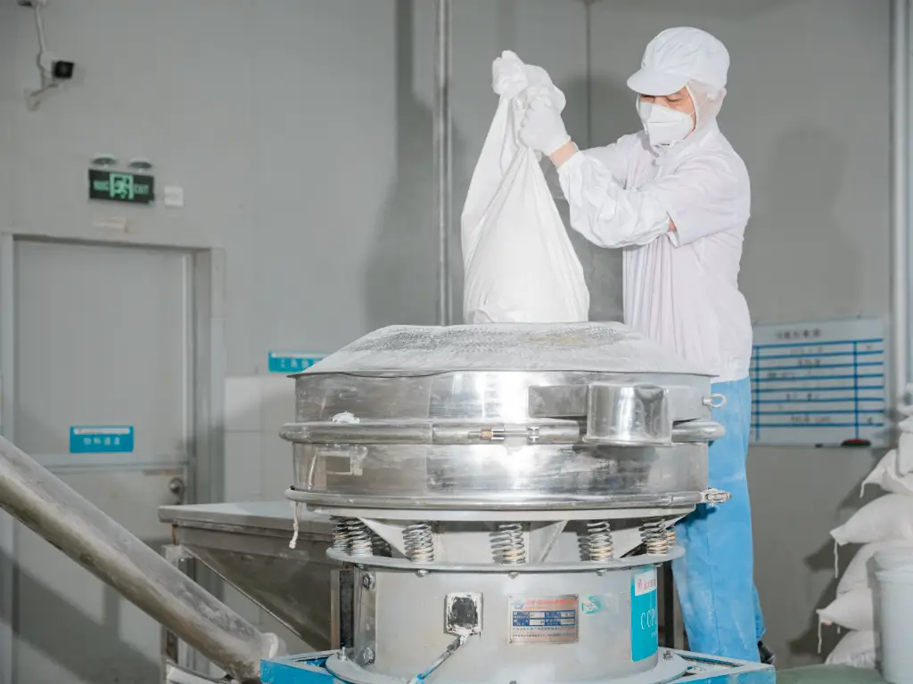 Quality control staff pour flour into the pot and perform a sieve inspection for foreign matter